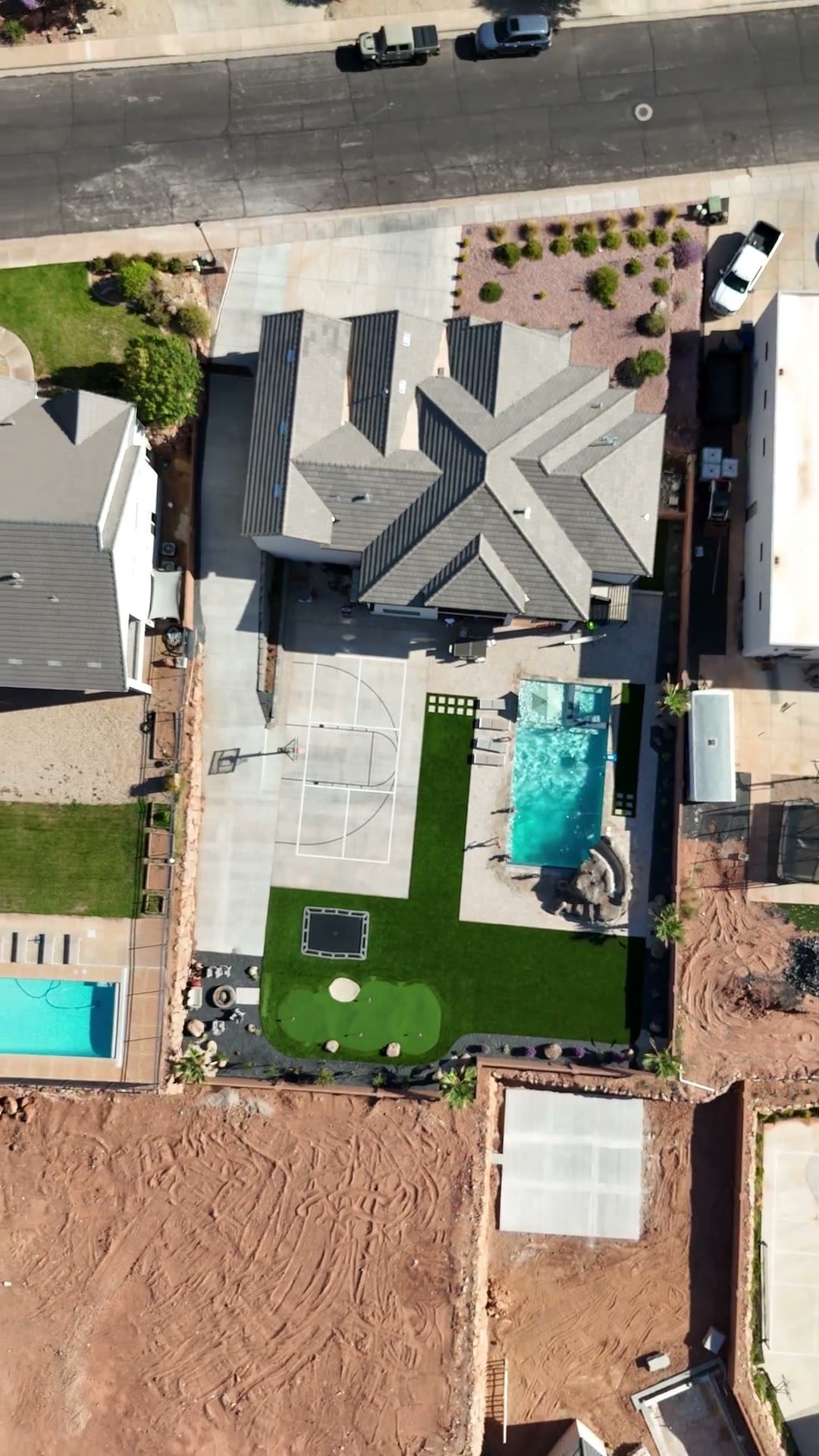Aerial view of a finished backyard with a pool, court and turf