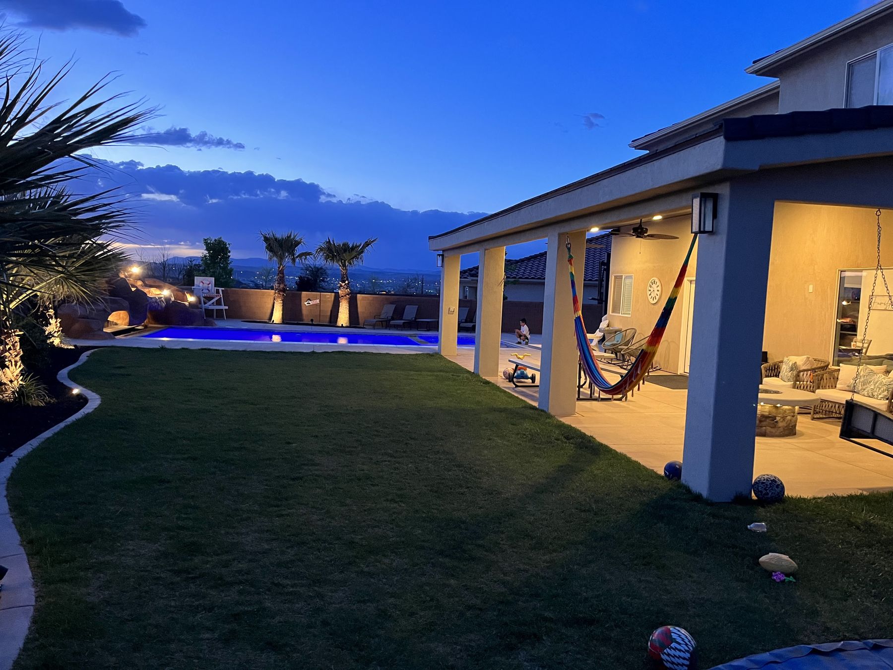 A covered patio and lawn at dusk