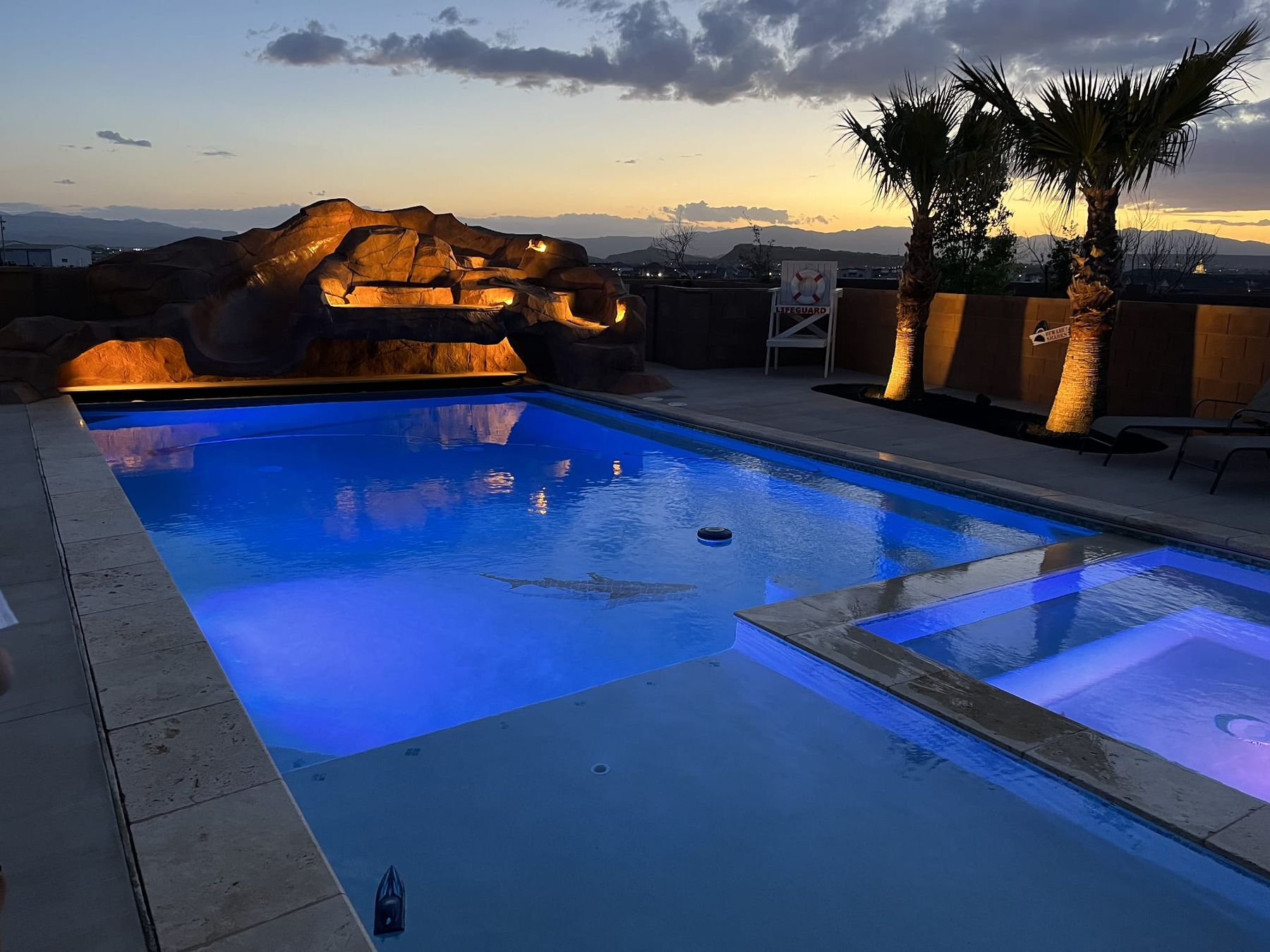 A custom pool with a rock feature at dusk