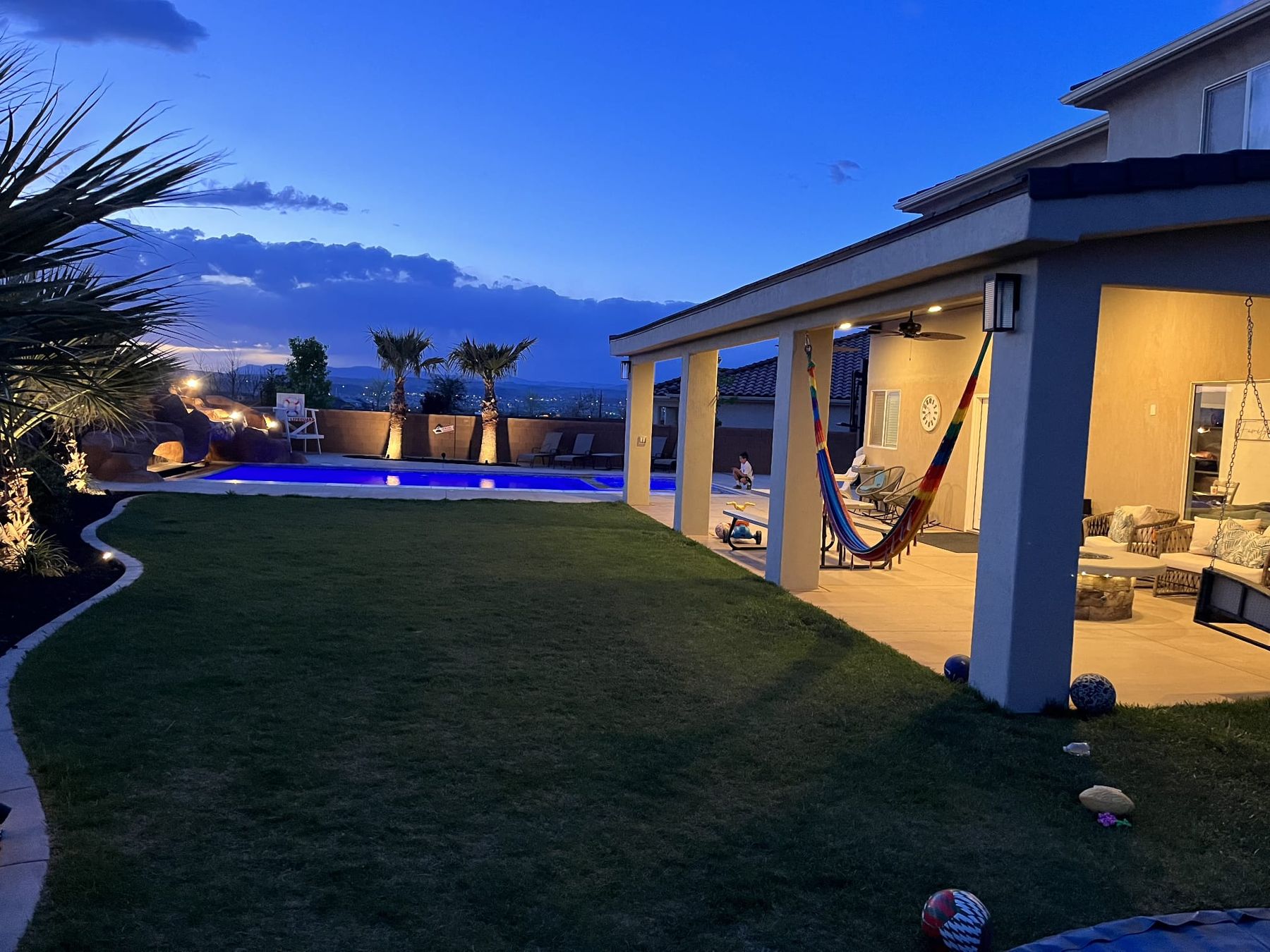 A backyard with a green lawn and a covered patio